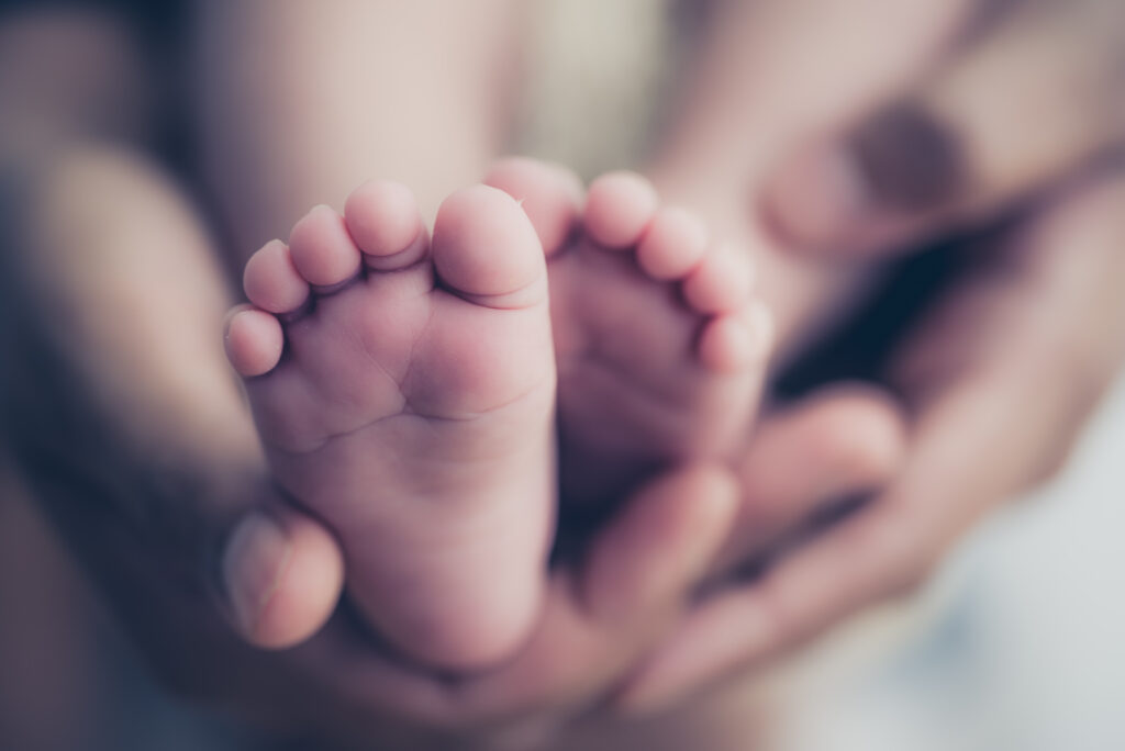 Füße eines Neugeborenen in den Händen der Eltern.